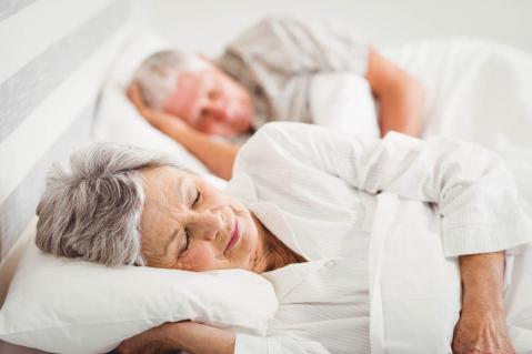 Ältere Frau und älterer Mann schlafen im Bett